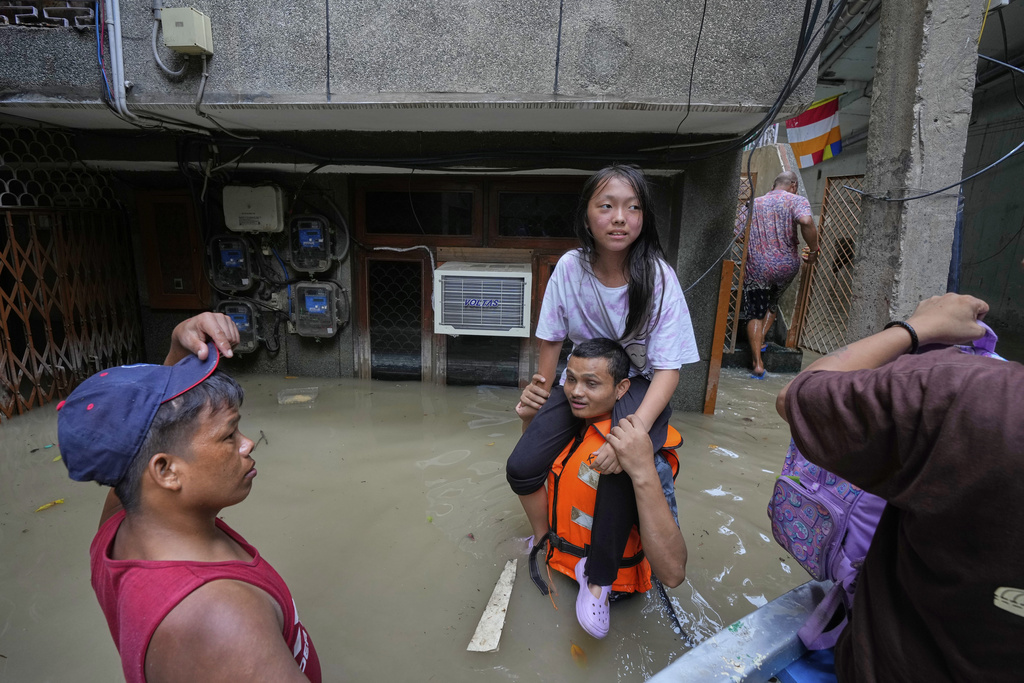 A volunteer lifts a young girl onto his shoulders, carrying her to a safer place after evacuating her and others by boat after the river Yamuna, swollen by incessant rain in the higher regions, overran its banks, in New Delhi, India, Friday, Sept. 5, 2025. (AP Photo/Manish Swarup)