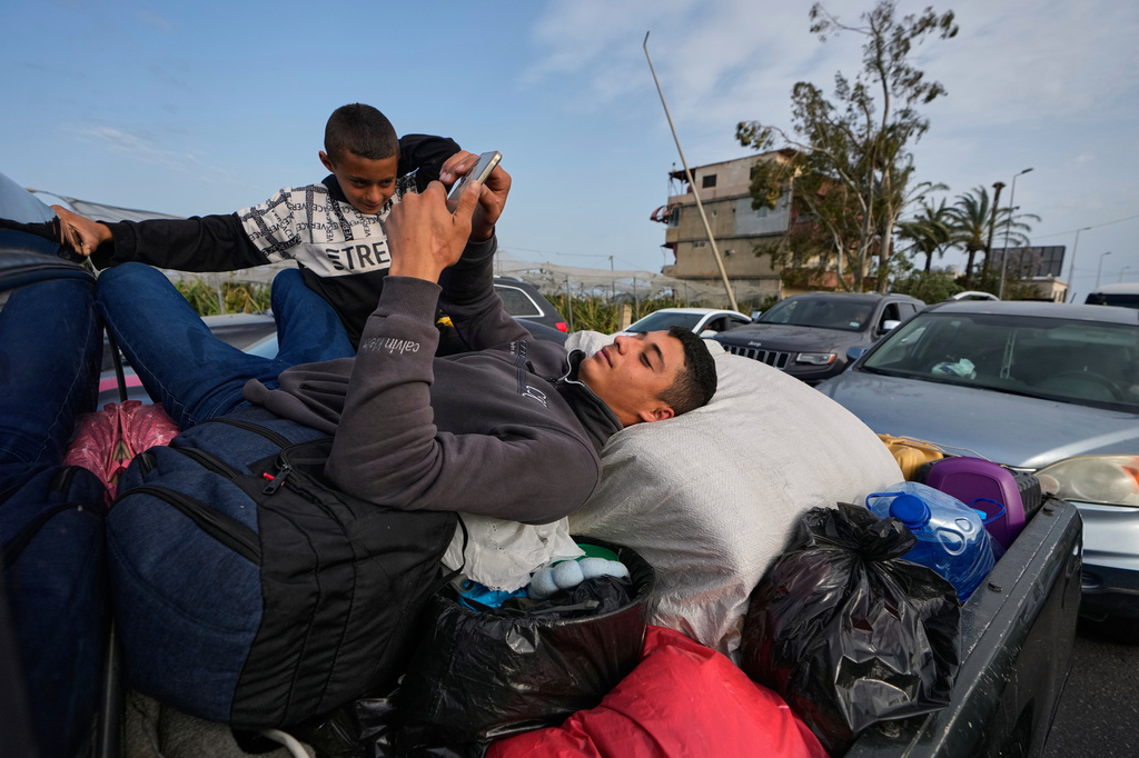 A displaced man lies over belongings on a mini pickup and checks his mobile phone, in Qasmiyeh near Tyre city, south Lebanon, as he returns with his family to their village following a ceasefire between Hezbollah and Israel, Friday, April 17, 2026. (AP Photo/Mohammed Zaatari)