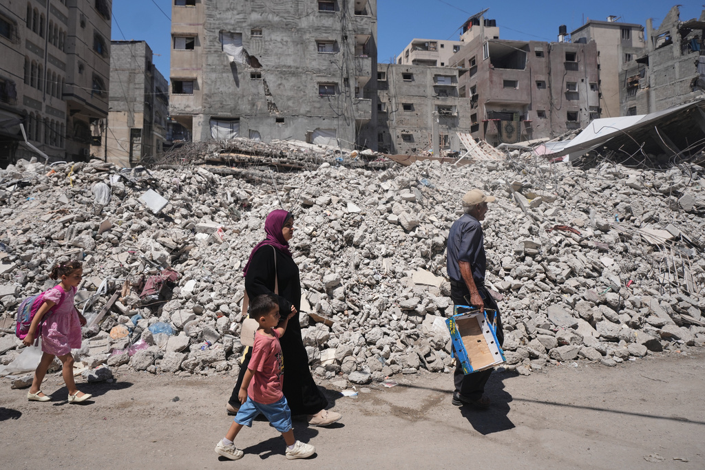 Palestinians walk amid the ruins of buildings destroyed by Israeli airstrikes during the war with Hamas, in Gaza City, Monday, Aug. 24, 2026. (AP Photo/Jehad Alshrafi)