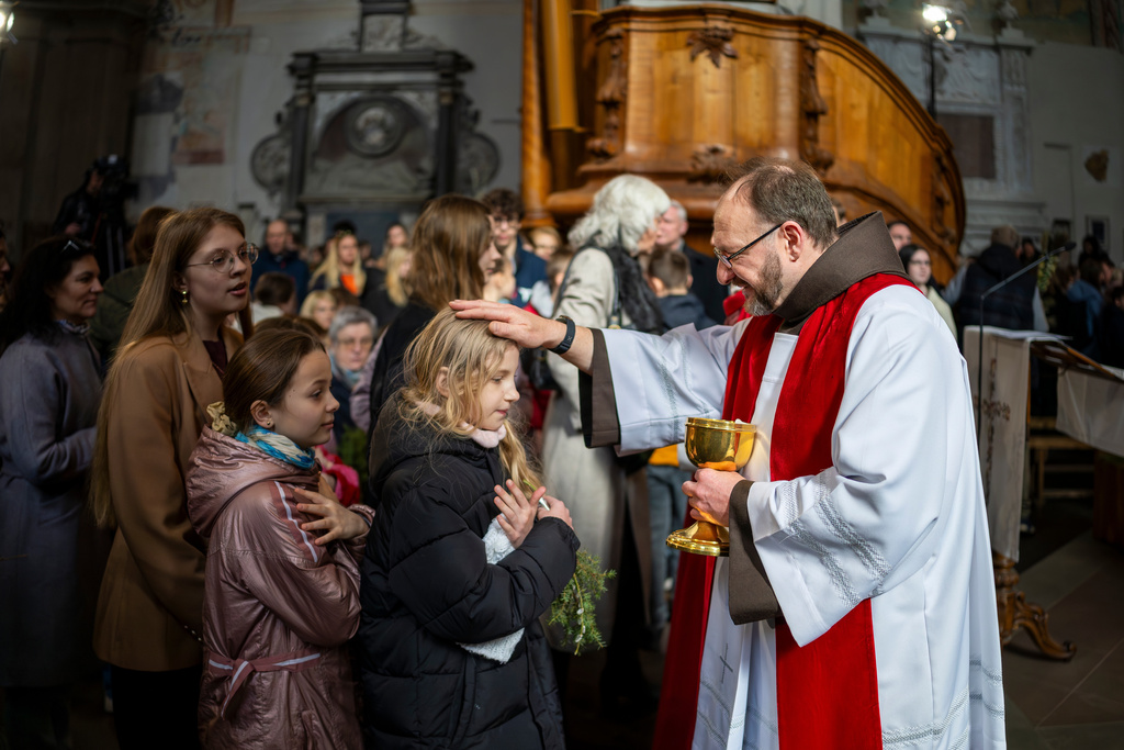 A priest distributes the Holy Communion during the Palm Sunday Mass at the St. Francis of Assisi Roman Catholic church in Vilnius, Lithuania, Sunday, March 29, 2026. (AP Photo/Mindaugas Kulbis)