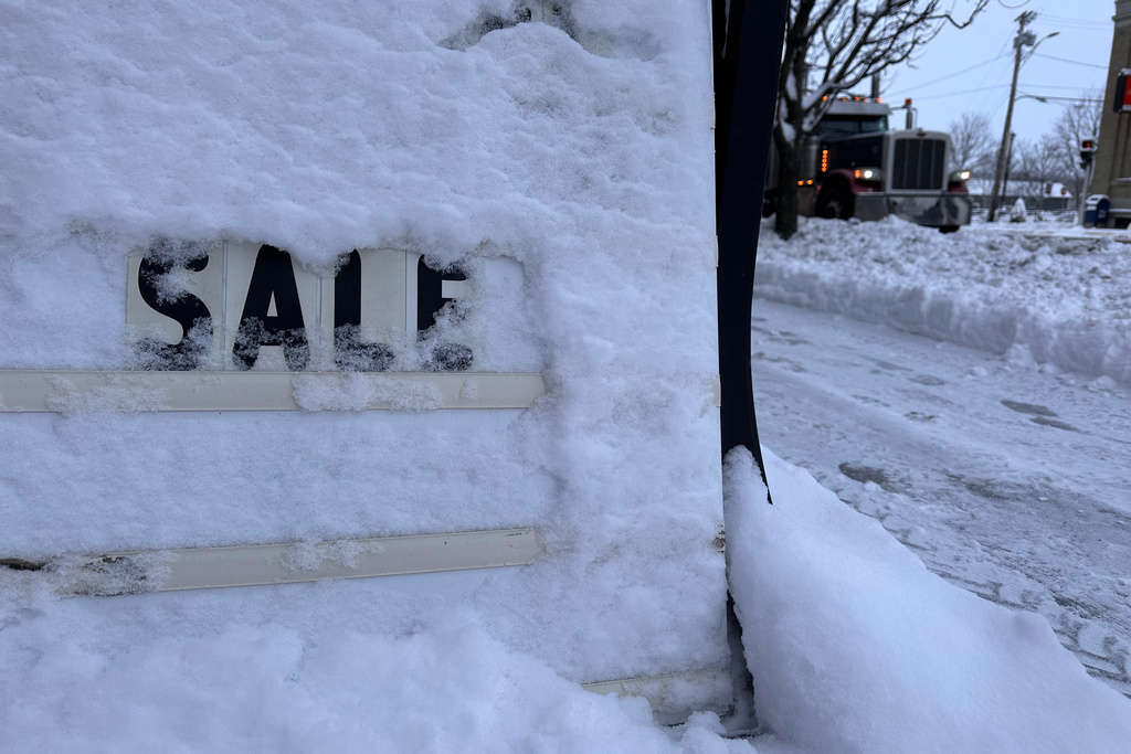 A store's promotional sign is snowed under in Lowville, N.Y., on Friday, Nov. 28, 2025. (AP Photo/Cara Anna)