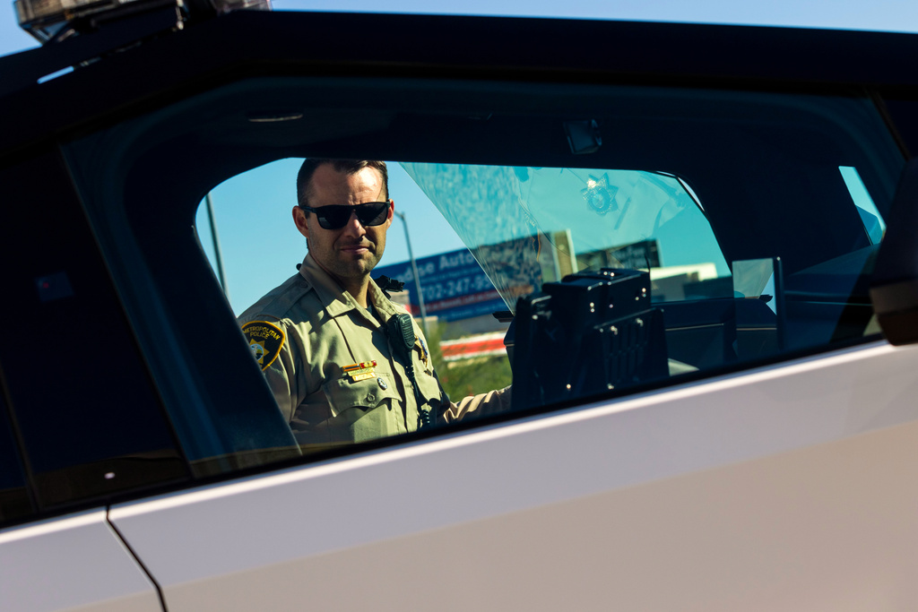 A member of the Las Vegas Police Department inspects a Tesla Cybertruck, part of the department's fleet of vehicles, in Las Vegas on Tuesday Oct, 28th 2025. (AP Photo/Ty ONeil)