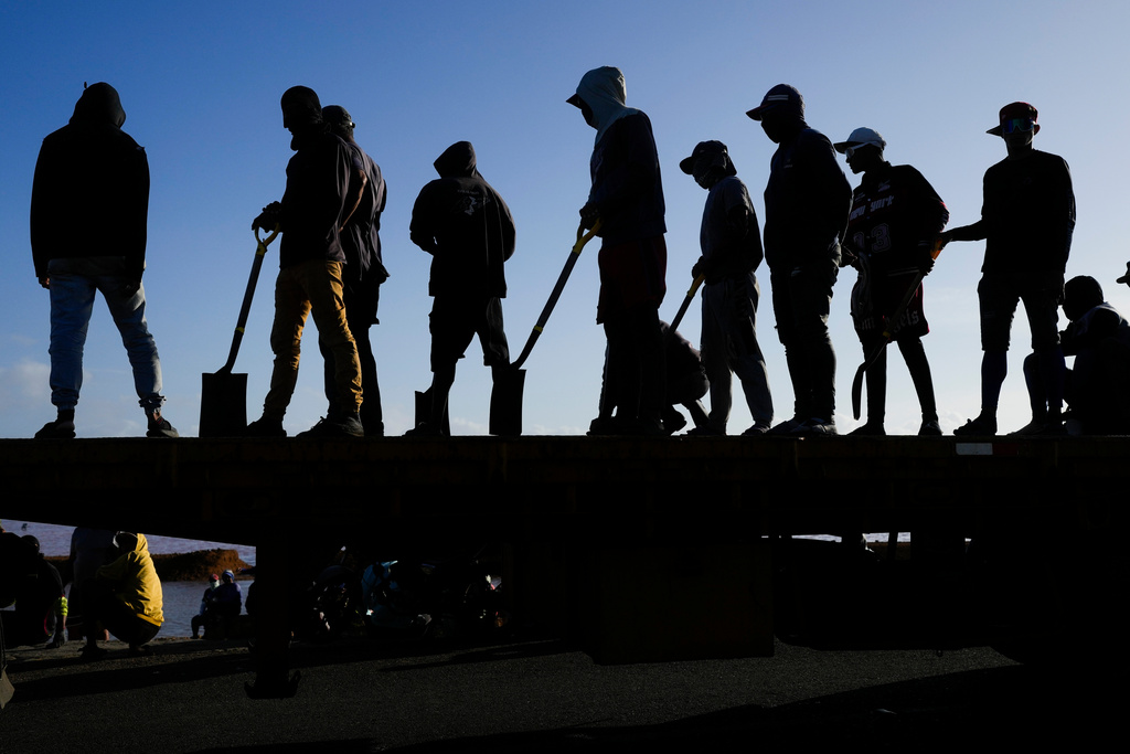 Workers stand atop a truck being loaded with salt at the Salinas de Las Cumaraguas salt ponds on the Paraguana Peninsula in Falcon state, Venezuela, Thursday, Jan. 15, 2026.. (AP Photo/Matias Delacroix)