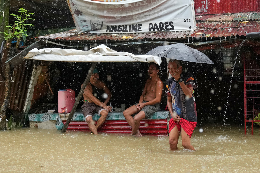 Residents stay at a store along floodwaters caused by heavy seasonal monsoon rains at Bagong Silangan village in Quezon city, Metro Manila, Philippines, Monday, Aug. 10, 2026. (AP Photo/Aaron Favila)
