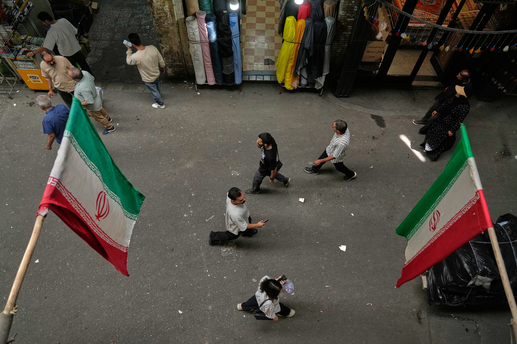 People walk as Iranian flags hang in the Grand Bazaar in Tehran, Sunday, May 3, 2026. (AP Photo/Vahid Salemi)
