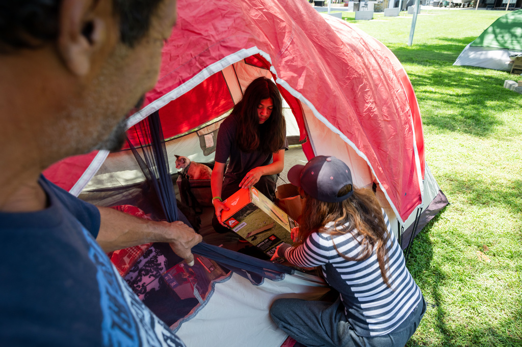 Evacuees Rodger Macias, left, his wife Alendera Marcias, and son, Adam Marcias, set up a tent outside the Elks Lodge in Garden Grove, Calif., on Monday, May 25, 2026. (AP Photo/Ethan Swope)