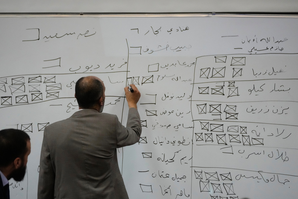 A Syrian election official writes on a board during the counting of ballots shortly after polling stations closed at Latakia's Governor building, in the coastal city of Latakia, Syria, Sunday, Oct. 5, 2025. (AP Photo/Hussein Malla)