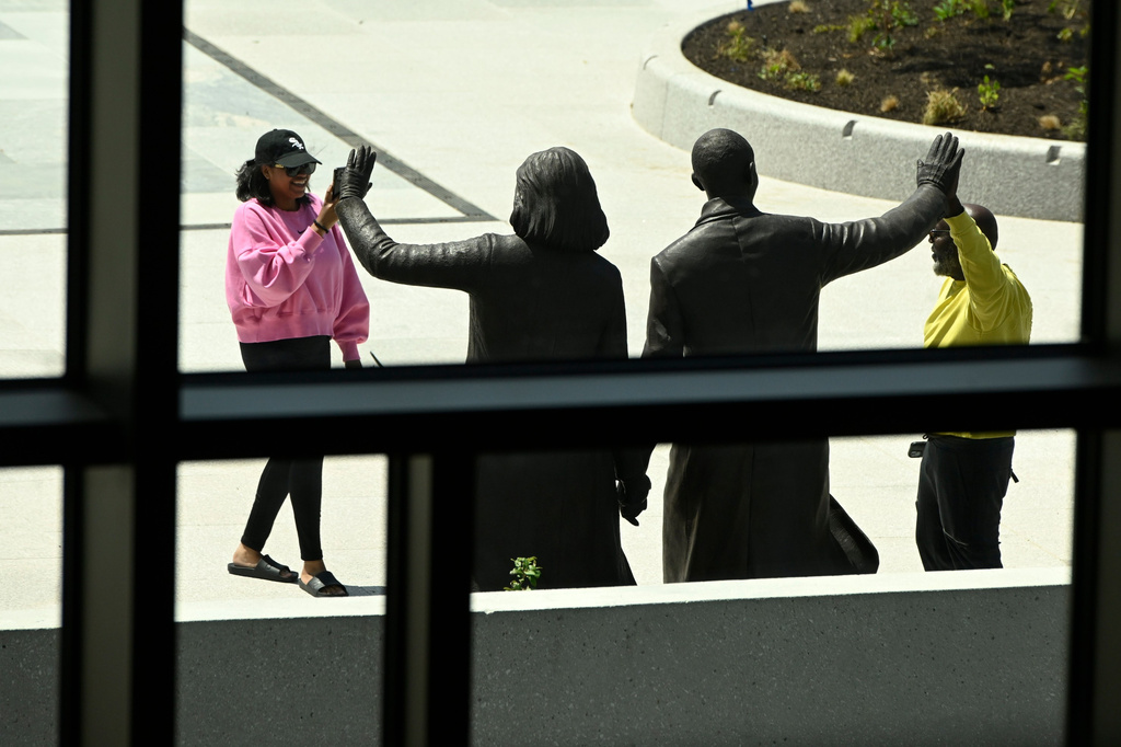 A visitor poses with statues of former President Barack Obama and former First Lady Michelle Obama at the Obama Presidential Center in Chicago, Thursday, May 28, 2026. (AP Photo/Paul Beaty)