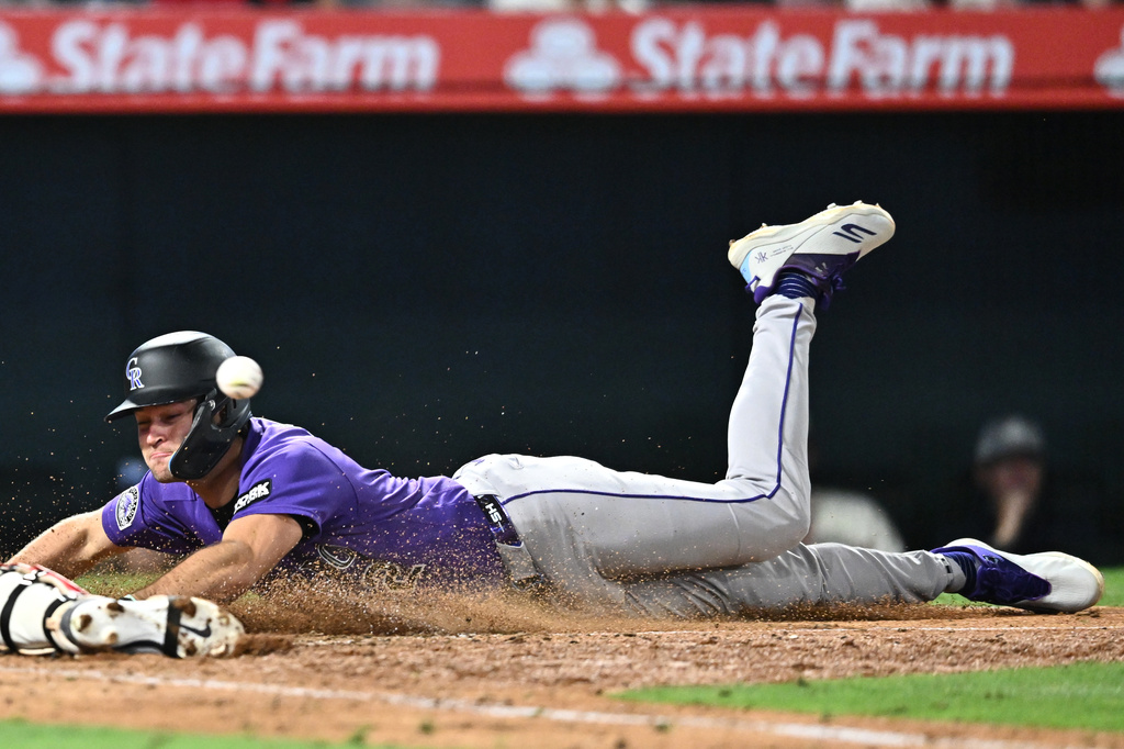 Colorado Rockies' Kyle Karros dives safely to score during the eighth inning of a baseball game against the Los Angeles Angels, Monday, June 1, 2026, in Anaheim, Calif. (AP Photo/William Liang)
