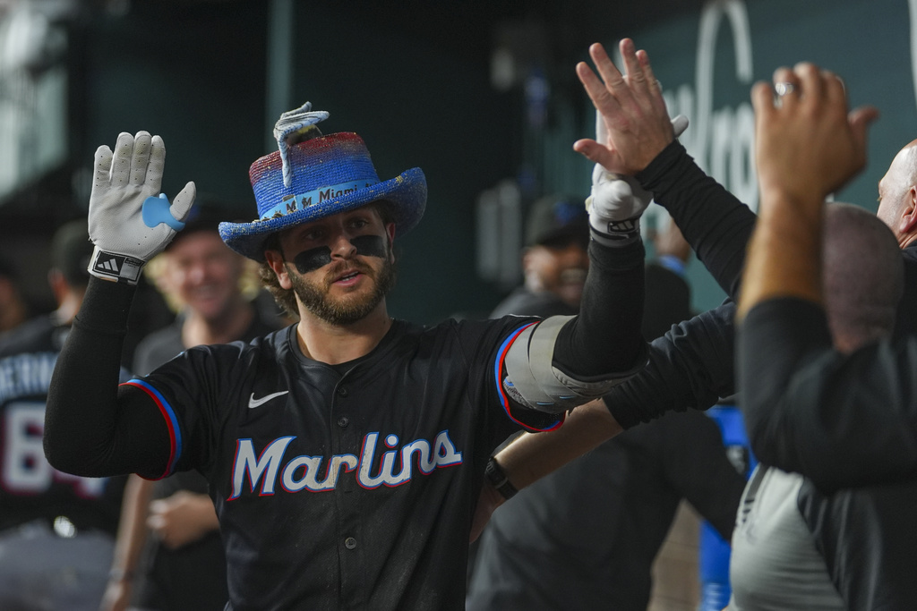Miami Marlins' Connor Norby is greeted in the dugout after hitting a solo home run off Texas Rangers pitcher Jack Leiter during the sixth inning of a baseball game Saturday, Sept. 20, 2025, in Arlington, Texas. (AP Photo/Julio Cortez)