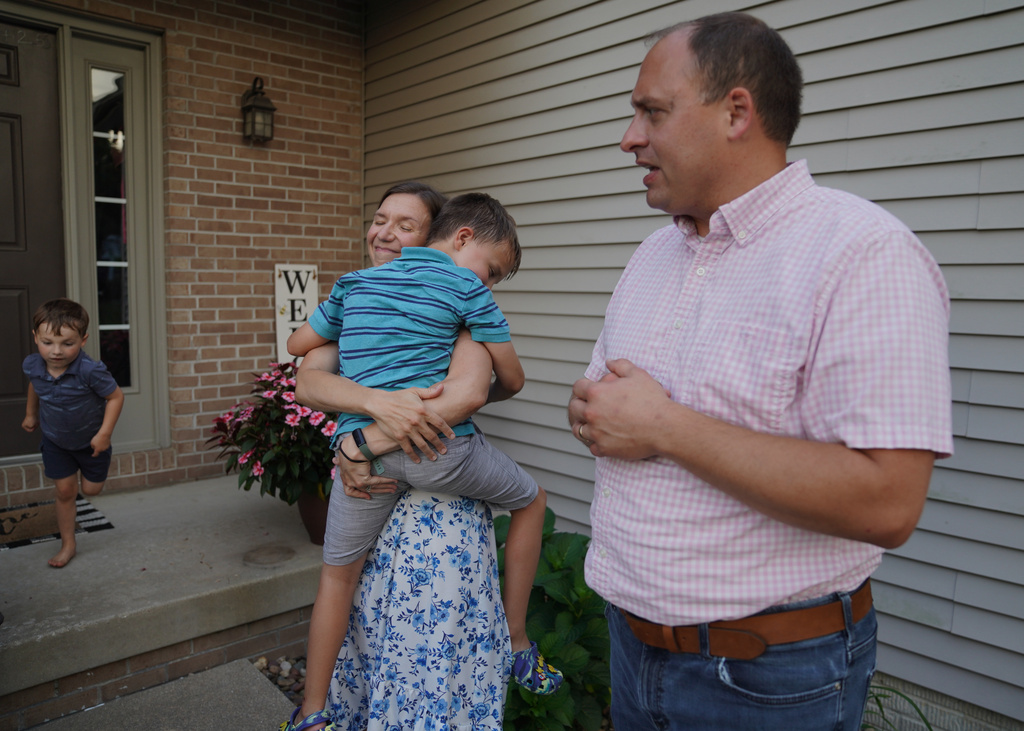 Lizzy Taggart holds her son Fulton, 8, while standing with her husband, Joe, outside their home in Bloomington, Ill., on July 16, 2026. (AP Photo/Jessie Wardarski)
