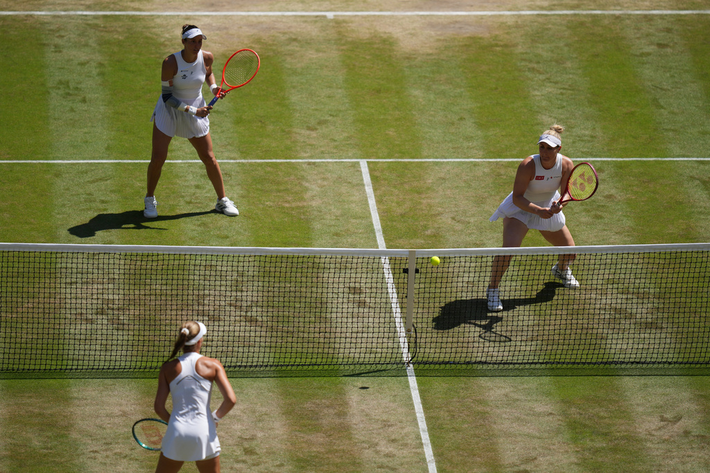 Luisa Stefani of Brazil, top left, and Gabriela Dabrowski of Canada, return the ball to Kristina Mladenovic of France, bottom, and Guo Hanyu of China, not pictured, in the women's doubles final at Wimbledon Tennis Championships in London, Sunday, July 12, 2026. (AP Photo/Kirsty Wigglesworth)