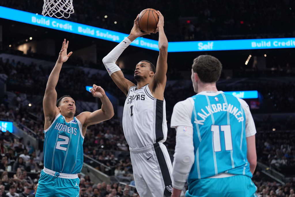 San Antonio Spurs forward Victor Wembanyama (1) drives to the basket against Charlotte Hornets forward Grant Williams (2) during the first half of an NBA basketball game in San Antonio, Saturday, March 14, 2026. (AP Photo/Eric Gay)