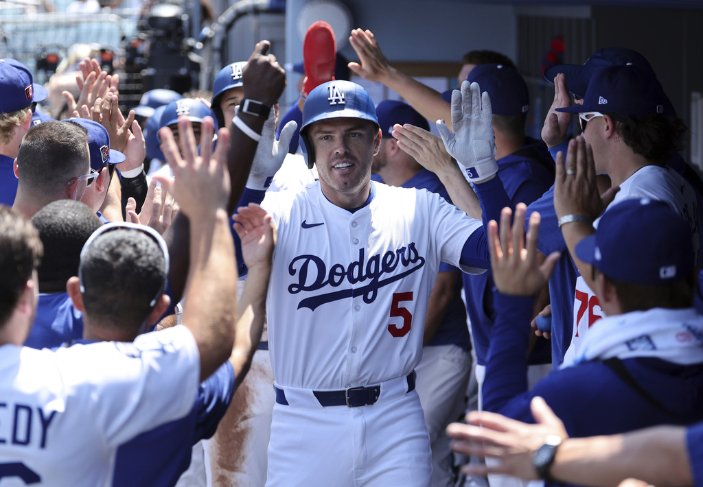 Los Angeles Dodgers' Freddie Freeman is congratulated in the dugout after hitting a three-run home run to score Shohei Ohtani and Mookie Betts against the San Diego Padres pitcher Yu Darvish during the first inning of a baseball game, Sunday, Aug. 17, 2025, in Los Angeles. (AP Photo/Kevork Djansezian)