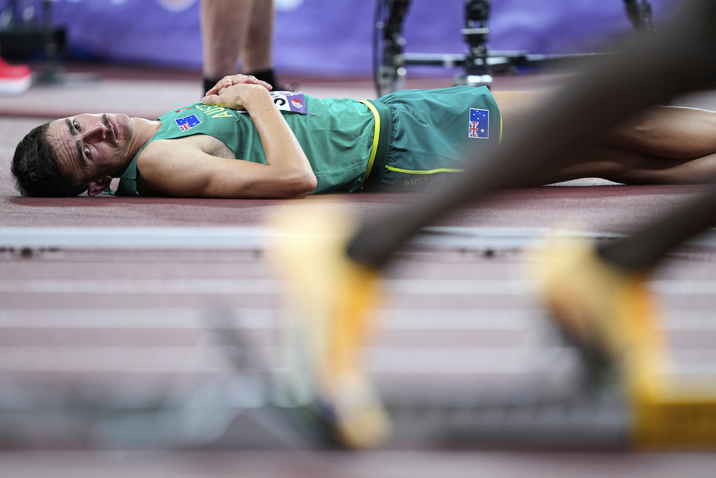 Australian high jumper Brandon Starc lays on the side of the track and watches the start of a men's 400 meters heat at the World Athletics Championships in Tokyo, Sunday, Sept. 14, 2025. (AP Photo/Petr David Josek)