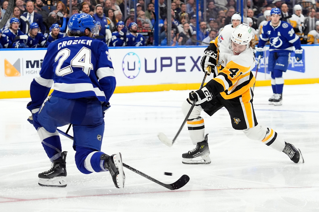 Pittsburgh Penguins right wing Ville Koivunen (41) takes a shot in front of Tampa Bay Lightning defenseman Max Crozier (24) during the third period of an NHL hockey game Thursday, Dec. 4, 2025, in Tampa, Fla. (AP Photo/Chris O'Meara)