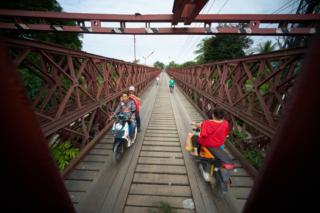Motorcyclists cross the Old French Bridge, a French colonial-era steel truss bridge that remains a key local crossing over the Nam Khan River in Luang Prabang, Laos, Wednesday, Nov. 5, 2025. (AP Photo/Eugene Hoshiko)