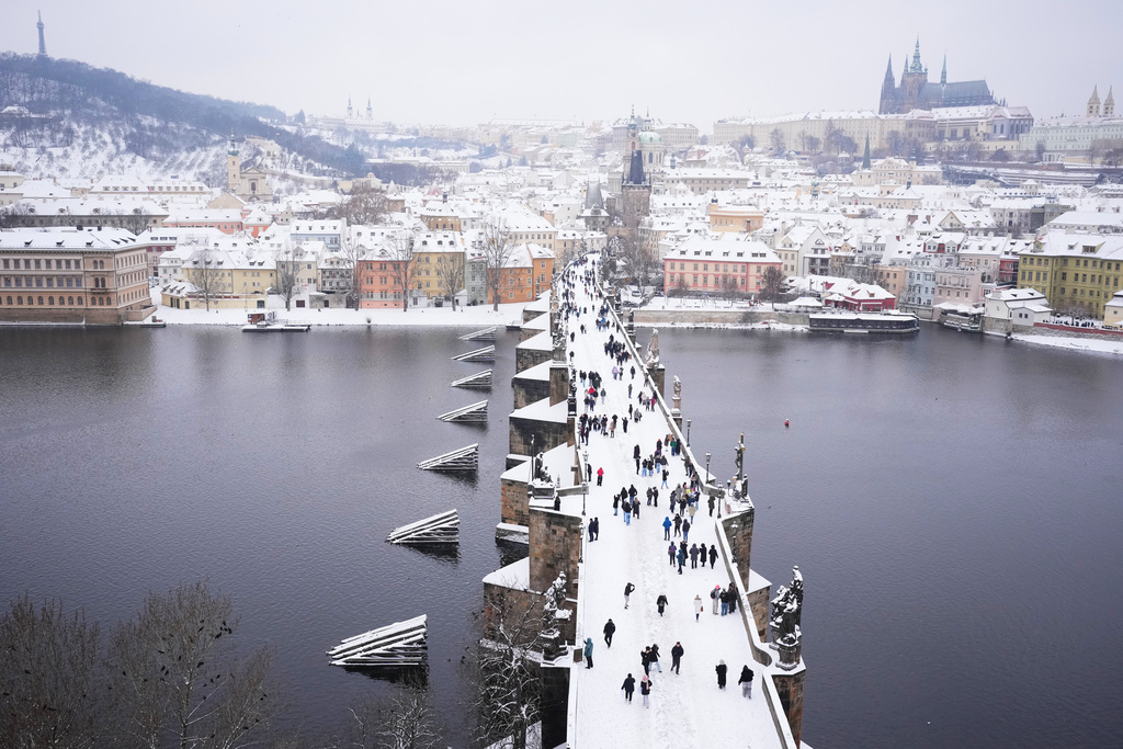 People cross the medieval Charles Bridge after a heavy snowfall in Prague, Czech Republic, Friday, Jan. 9, 2026. (AP Photo/Petr David Josek)
