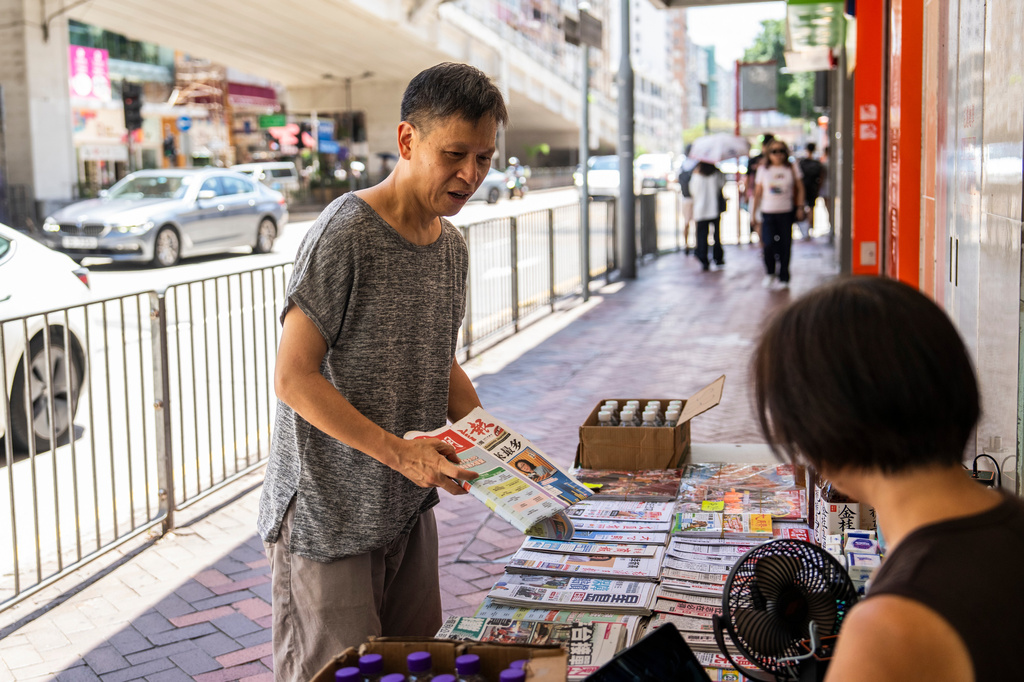 Pro-democracy activist Tang Ngok-kwan buys newspapers at a street newsstand in Mong Kok, Hong Kong, Saturday, July 11, 2026. (AP Photo/Chan Long Hei)