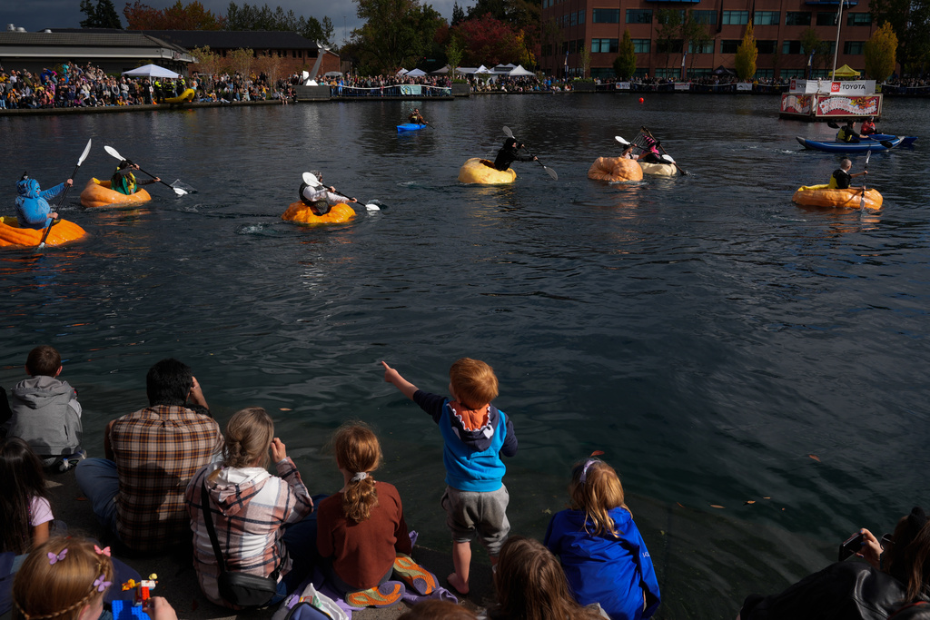 A child points to people racing giant pumpkins during the West Coast Giant Pumpkin Regatta on Sunday, Oct. 19, 2025, in Tualatin, Ore. (AP Photo/Jenny Kane)