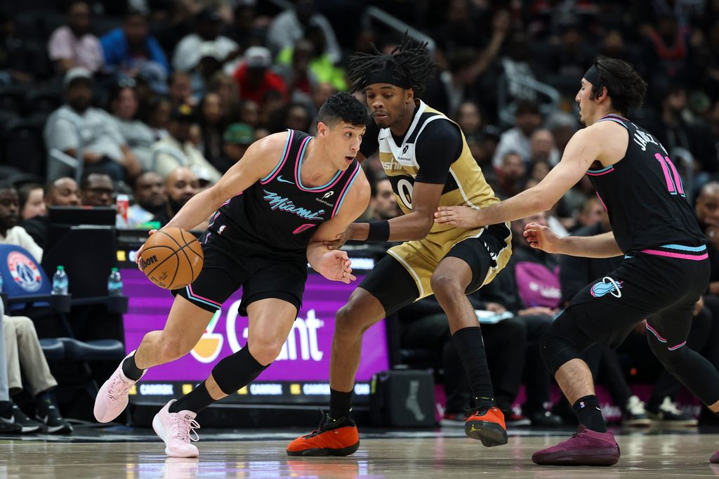 Miami Heat forward Simone Fontecchio, left, handles the ball as Washington Wizards guard Bilal Coulibaly, center, defends during the first half of an NBA basketball game, Friday, April 10, 2026, in Washington. (AP Photo/Terrance Williams)