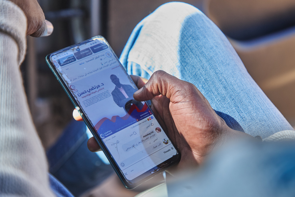 Dr. Mohammed Ibrahim checks his messages at Rwanda refugee camp in Tawila in Darfur, Sudan, Dec. 22, 2025. (AP Photo/Marwan Mohamed)
