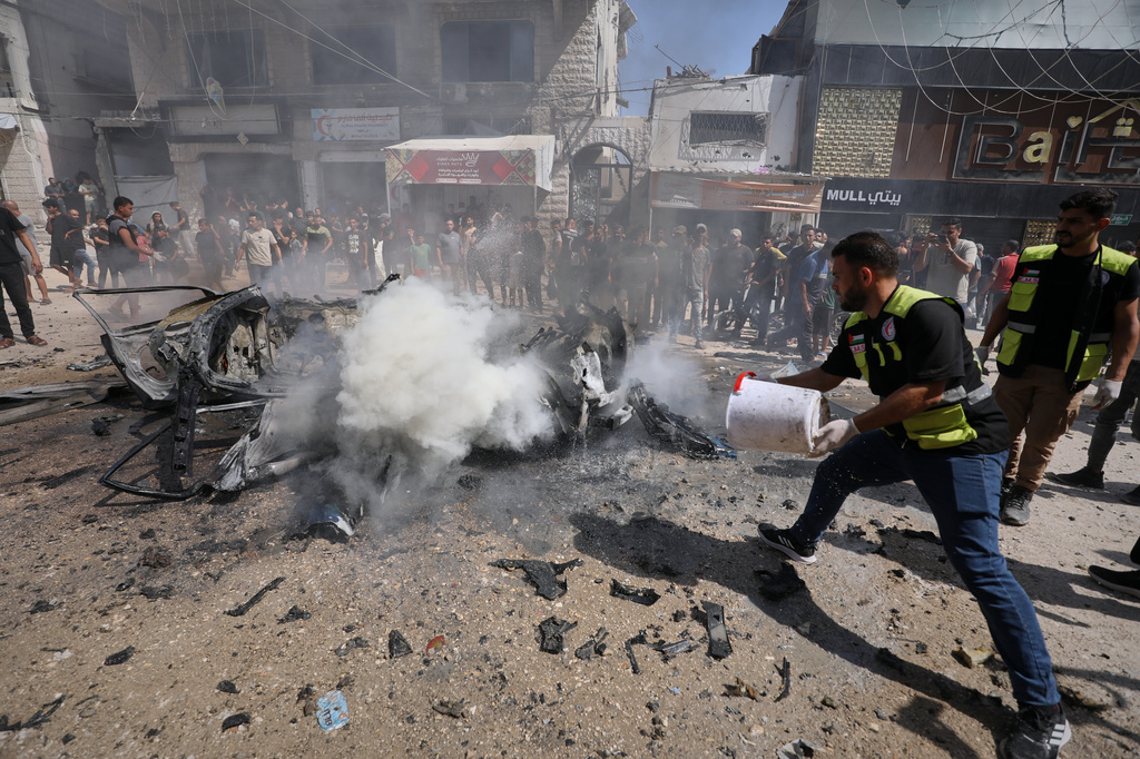 A Palestinian paramedic throws water onto the smoldering wreckage of a car after an Israeli strike in Gaza City, Monday, Aug. 31, 2026. (AP Photo/Yousef Alzanoun)