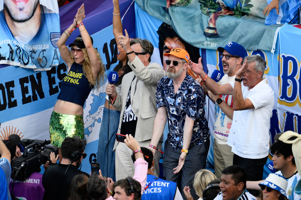 Actors Jason Sudeikis, second right, who plays Ted Lasso, and Brendan Hunt, center, who plays Coach Beard on the series Ted Lasso, lead the crowd in cheers before the World Cup quarterfinal soccer match between Switzerland and Argentina in Kansas City, Mo., Saturday, July 11, 2026. (AP Photo/Reed Hoffmann)