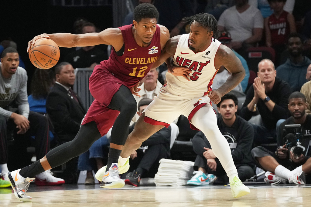 Cleveland Cavaliers forward De'Andre Hunter (12) dribbles the ball as Miami Heat guard Davion Mitchell (45) defends during the first half of an NBA basketball game Monday, Nov. 10, 2025, in Miami. (AP Photo/Marta Lavandier)