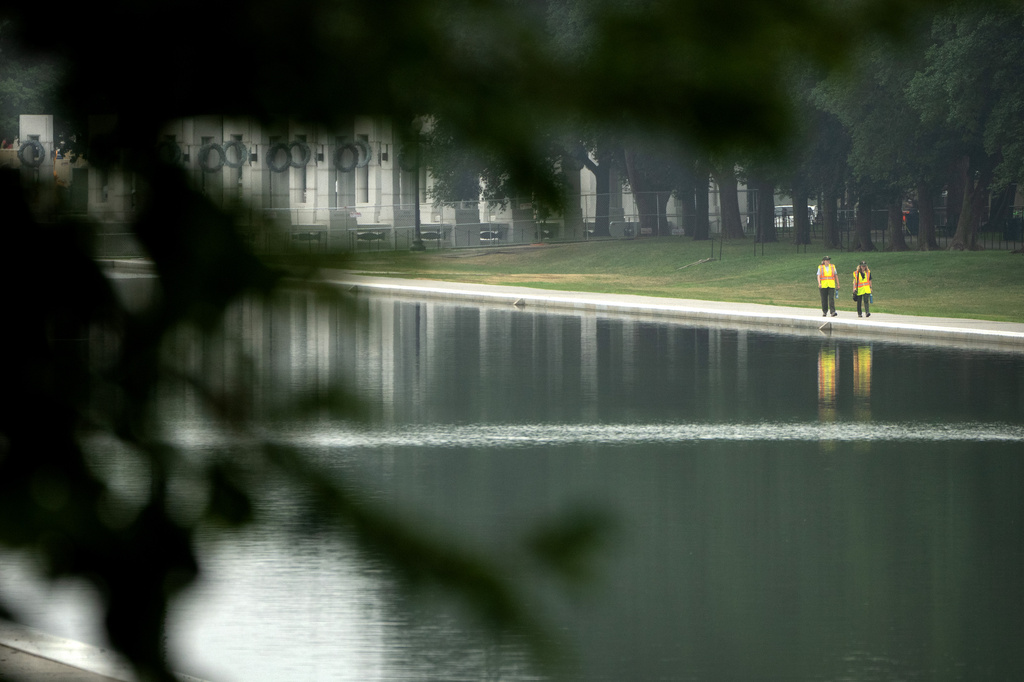 Workers pick up trash along the Lincoln Memorial Reflecting Pool, Tuesday, July 7, 2026, in Washington. (AP Photo/Mark Schiefelbein)