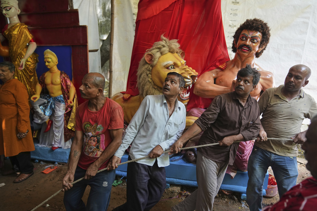 Workers pull ropes tied to the base of an idol of Durga as they move it onto a truck for transportation to a place of worship ahead of the Durga Puja festival in New Delhi, India, Sunday, Sept. 21, 2025. (AP Photo/Manish Swarup)