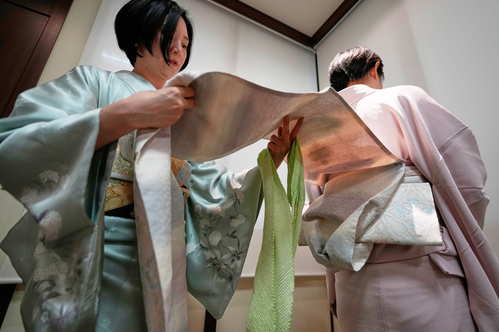 Nao Shimizu, Representative Director of Kimono Sunao Co., Ltd., left, demonstrates various ways of tying an obi on Emiko Terai during a kimono presentation in Tokyo on Tuesday, Nov. 11, 2025. (AP Photo/Eugene Hoshiko)
