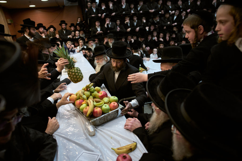 Ultra-Orthodox Jews from the Nadvorna Hasidic dynasty pass a platter of fruit during celebrations marking the Jewish holiday of Tu Bishvat, the "New Year of the Trees," in the ultra-Orthodox town of Bnei Brak, Israel, Monday, Feb. 2, 2026. (AP Photo/Oded Balilty)