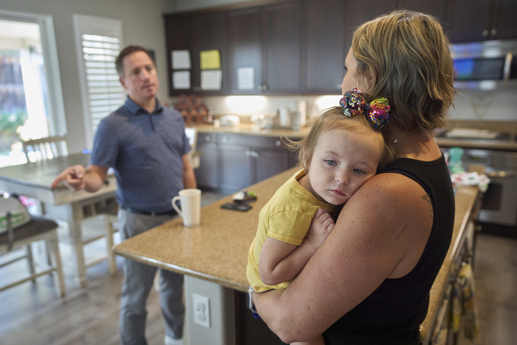 Emily Marris, right, holds her daughter, Brooklyn Marris, as she talks to her husband, Josh Marris, at their home in Winchester, Calif., on Thursday, Sept. 18, 2025. (AP Photo/Gregory Bull)