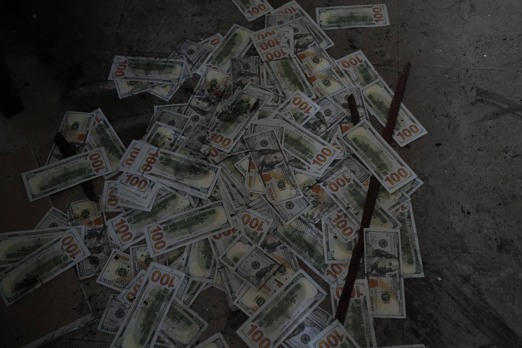 Fake dollar bills lie on the floor at a scam center in O'Smach, Cambodia, Monday, Feb. 2, 2026. (AP Photo/Sakchai Lalit)