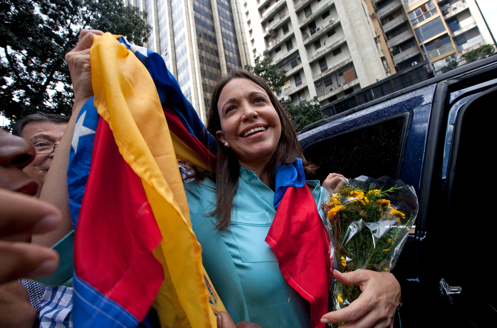 FILE - Former Congresswoman and opposition leader Maria Corina Machado holds up the Venezuelan flag outside of the Attorney General Office in Caracas, Venezuela, Wednesday, Dec. 3, 2014. (AP Photo/Ariana Cubillos, File)