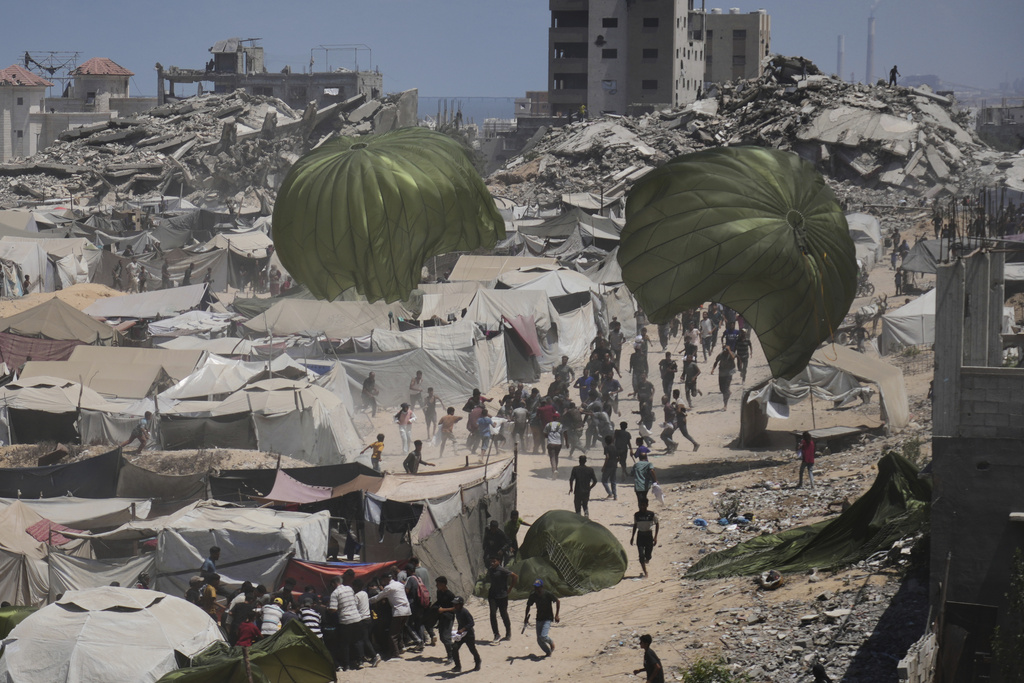 Palestinians rush to collect humanitarian aid airdropped by parachutes into Gaza City, northern Gaza Strip, Aug. 7, 2025. (AP Photo/Jehad Alshrafi)