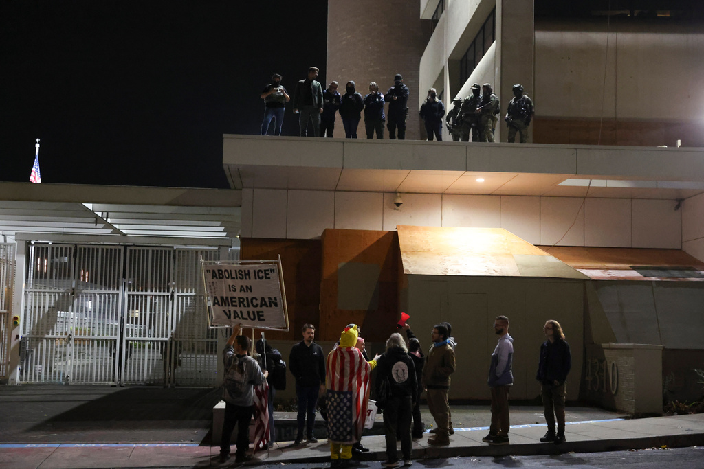 People protest outside a U.S. Immigration and Customs Enforcement facility as federal agents watch from the rooftop, in Portland, Oregon, Wednesday, Oct. 1, 2025. (AP Photo/Amanda Loman)