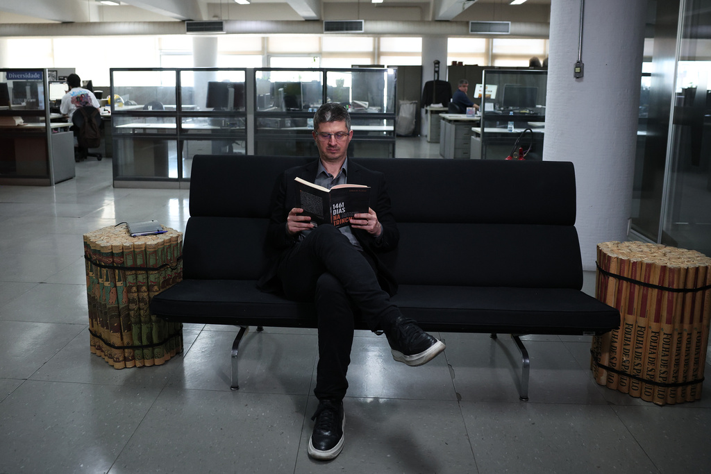 Journalist Eduardo Scolese reads his book "1461 days in the trench" during an interview in Sao Paulo, Wednesday, Nov. 19, 2025. (AP Photo/Ettore Chiereguini)