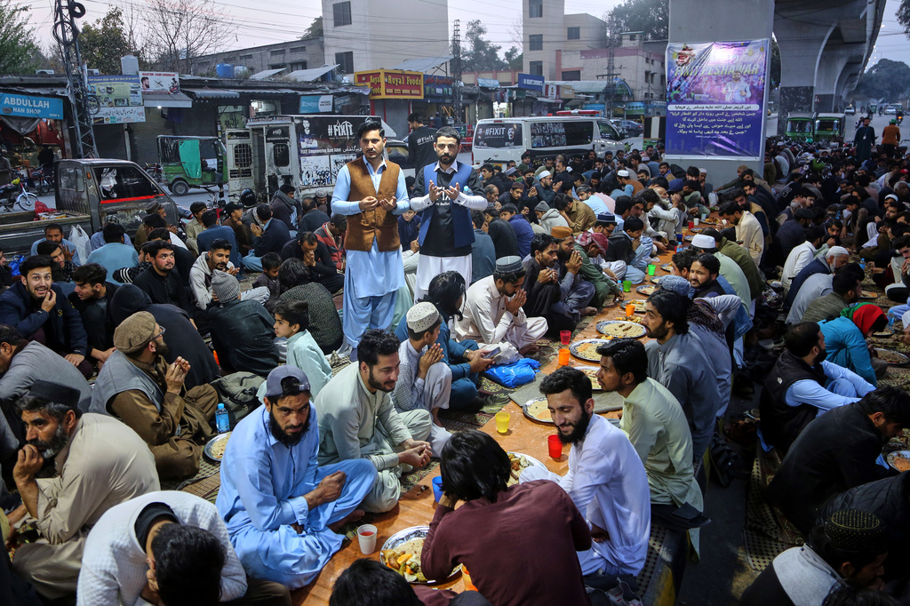 People pray before breaking their fast during the holy fasting month of Ramadan, at a free food distribution point, in Peshawar, Pakistan, Friday, Feb. 20, 2026. (AP Photo/Muhammad Sajjad)