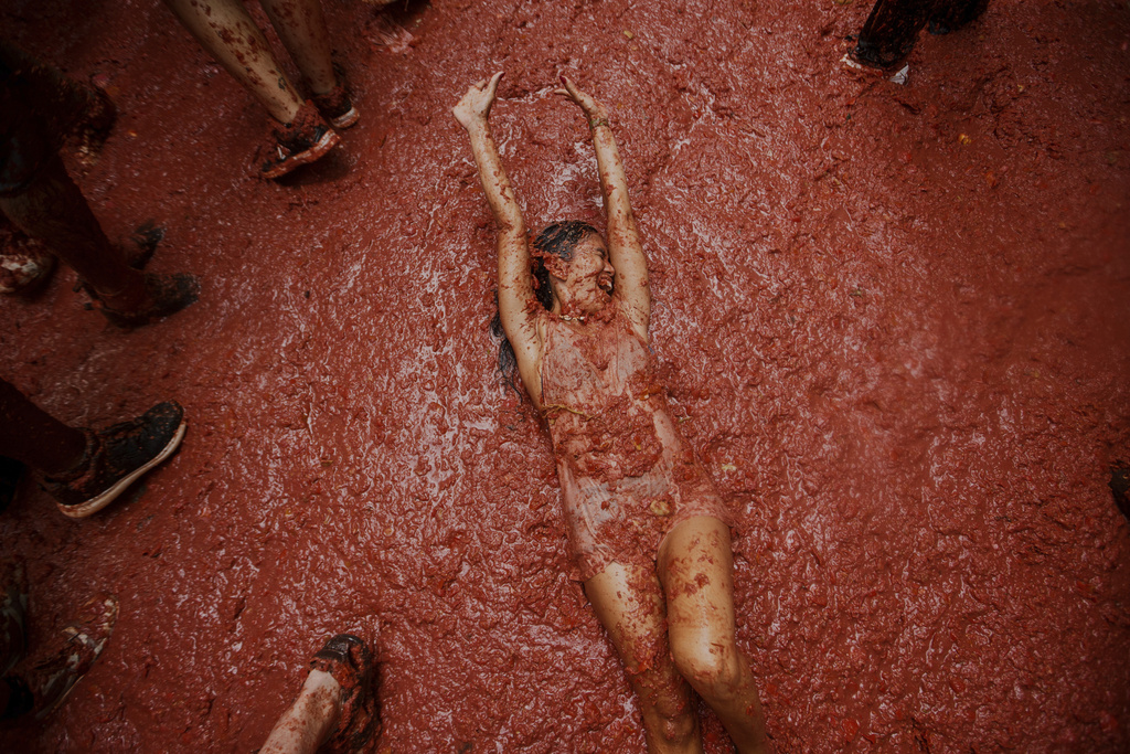 A woman reacts during the annual "Tomatina" tomato fight fiesta, in the village of Bunol near Valencia, Spain, Wednesday, Aug. 27, 2025. (AP Photo/Alberto Saiz)