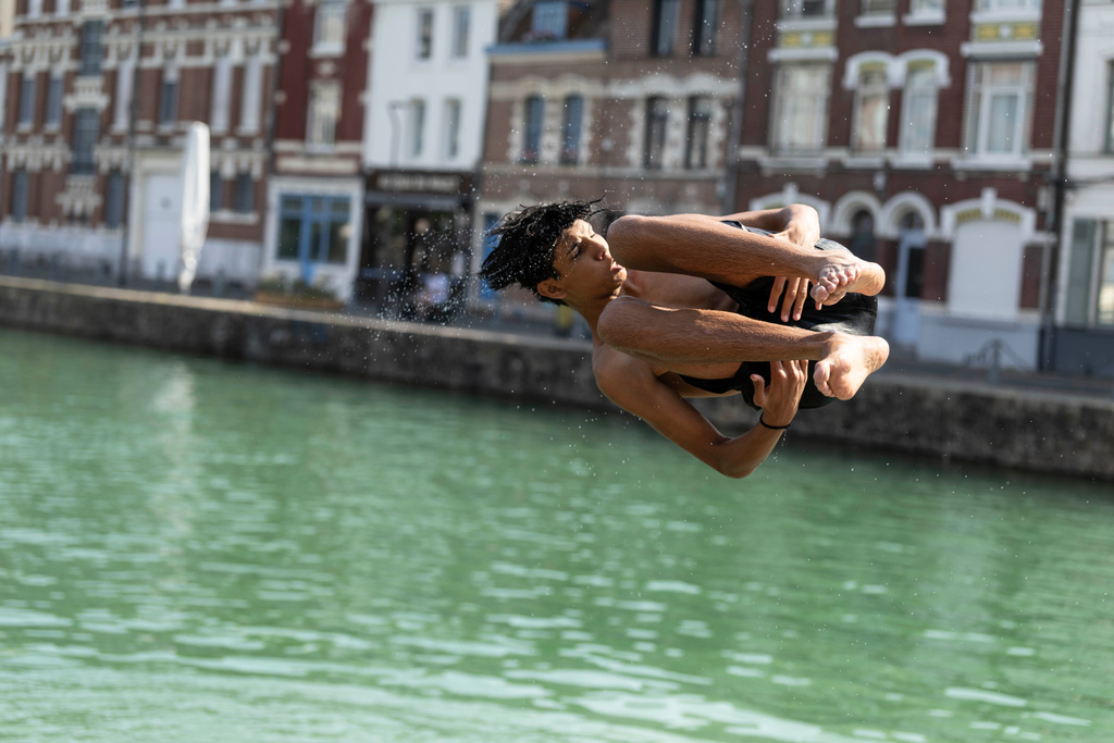 A young man dives into the water, in Lille, northern France, Monday June 22, 2026. (AP Photo/Jean-Francois Badias)