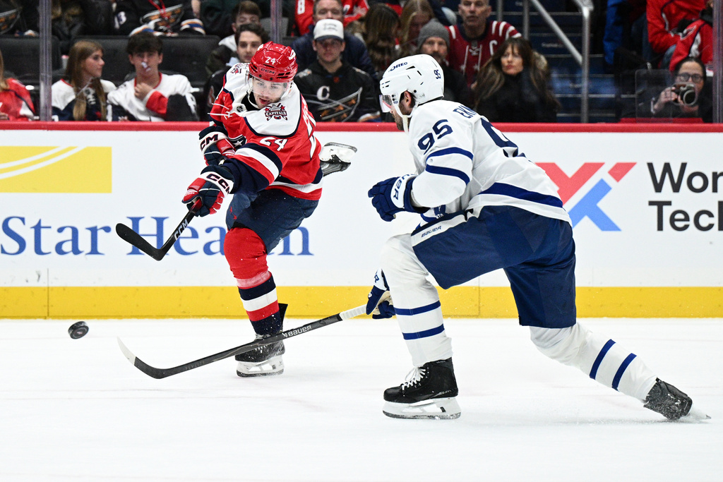 Washington Capitals center Connor McMichael (24) shoots the puck against Toronto Maple Leafs defenseman Oliver Ekman-Larsson (95) during the first period of an NHL hockey game, Friday, Nov. 28, 2025, in Washington. (AP Photo/Nick Wass)