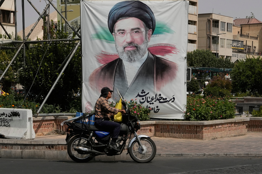 A man drives past a banner showing a portrait of the Iranian Supreme Leader Ayatollah Mojtaba Khamenei, in downtown Tehran, Iran, Monday, Aug. 31, 2026. (AP Photo/Vahid Salemi)