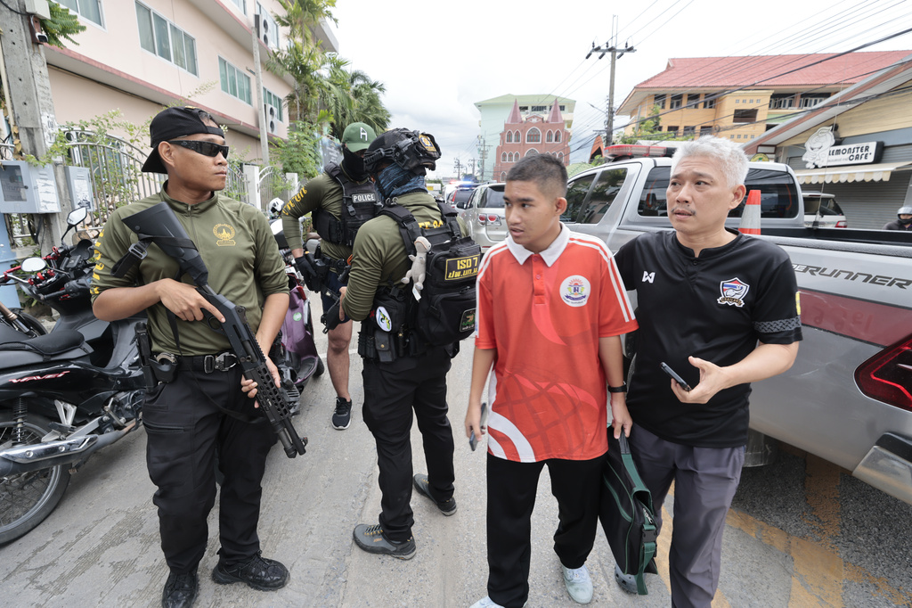 A schoolboy walks past policemen keeping guard after a shooting incident at the Debsirin Nonthaburi School in Thailand's Nonthaburi province, Friday, Aug. 7, 2026. (AP Photo/Wason Wanichakorn)