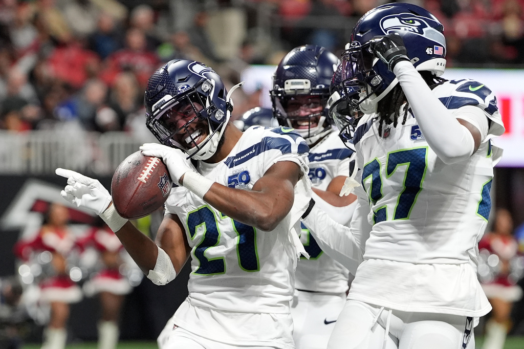 Seattle Seahawks cornerback Devon Witherspoon (21) celebrates his fumble recovery against the Atlanta Falcons with teammates, including cornerback Riq Woolen (27) during the second half of an NFL football game, Sunday, Dec. 7, 2025, in Atlanta. (AP Photo/Brynn Anderson)