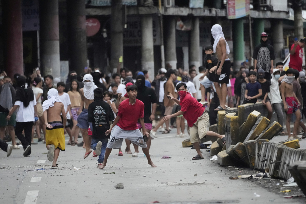 Anti-corruption protesters throw rocks at police during clashes as they tried to enter the Malacanang presidential palace compound in Manila, Philippines on Sunday, Sept. 21, 2025. (AP Photo/Aaron Favila)