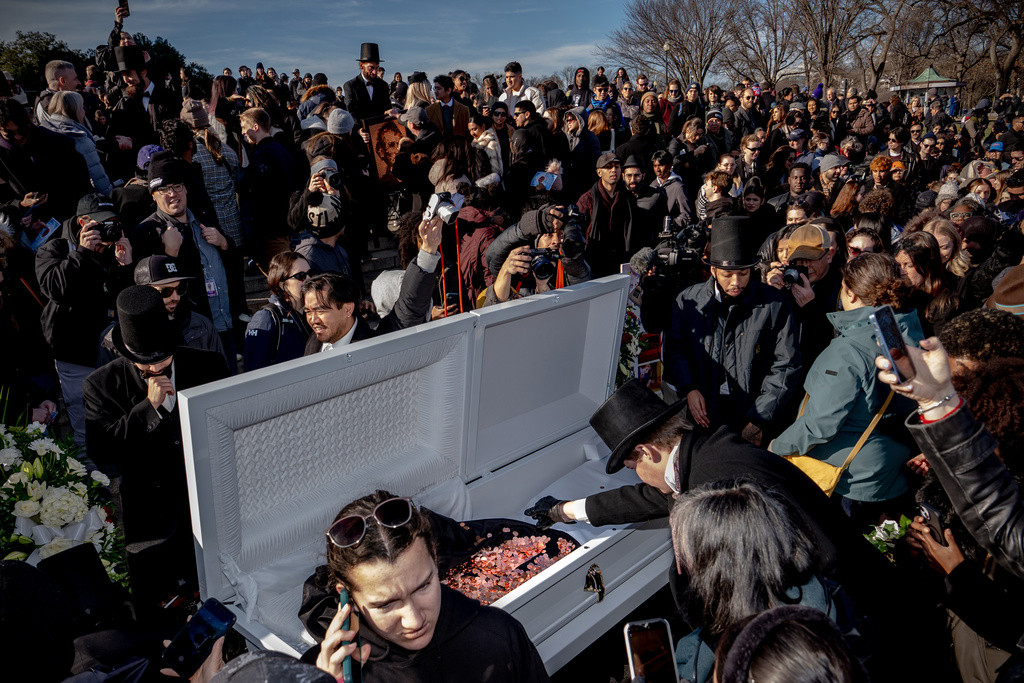 People gather to throw pennies into a casket during a mock funeral for the penny, which was discontinued earlier this year, Saturday, Dec. 20, 2025, in front of the Lincoln Memorial in Washington. (AP Photo/Julia Demaree Nikhinson)