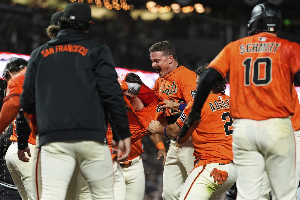 San Francisco Giants' Patrick Bailey, center left, is mobbed by teammates after hitting a game-winning grand slam during the 10th inning of a baseball game against the Los Angeles Dodgers, Friday, Sept. 12, 2025, in San Francisco. (AP Photo/Godofredo A. Vásquez)