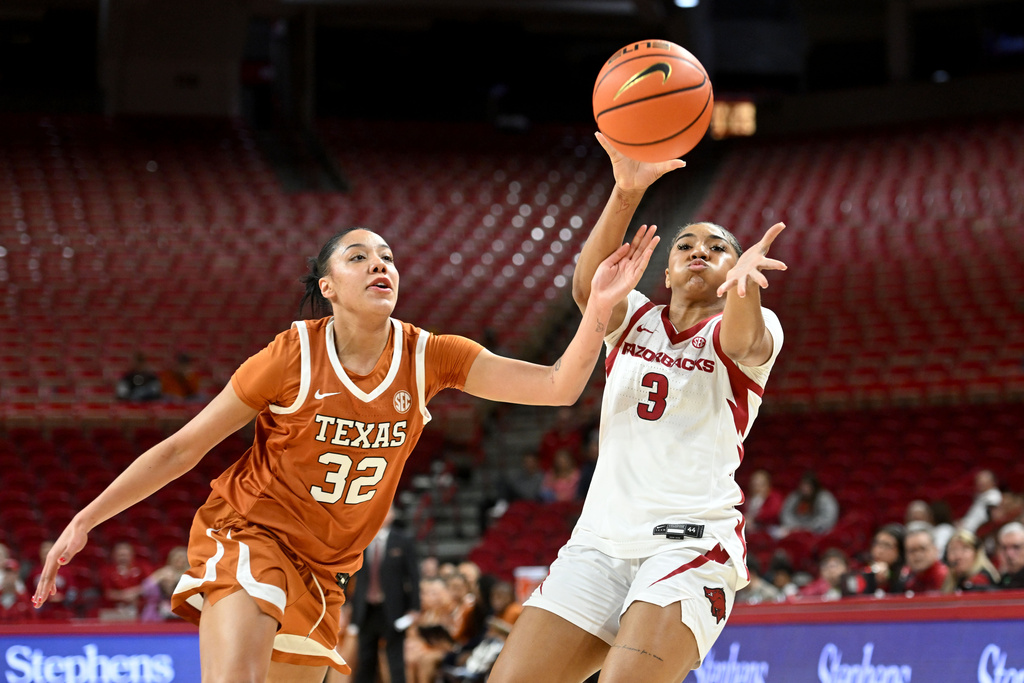Texas forward Teya Sidberry (32) tries to intercept a pass to Arkansas guard Harmonie Ware (3) during an NCAA college basketball game Thursday, Feb. 19, 2026, in Fayetteville, Ark. (AP Photo/Michael Woods)